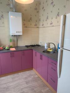 eine Küche mit lila Schränken und einem weißen Kühlschrank in der Unterkunft Александра Поля проспект Апартаменты in Dnipro
