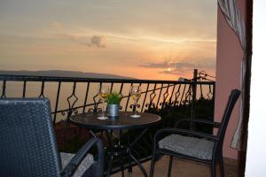 stół i krzesła na balkonie z widokiem na zachód słońca w obiekcie Apartments & Room MaDi w mieście Senj