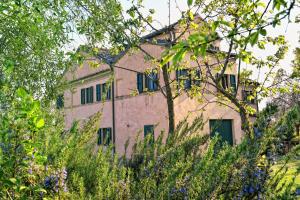 un antiguo edificio detrás de algunos árboles y arbustos en I Ciliegi, en Osimo