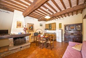Agriturismo Lodolazzo في كورتونا: غرفة معيشة مع مطبخ وطاولة مع كراسي