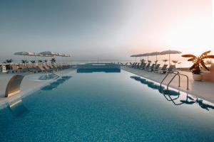 a large swimming pool with chairs and umbrellas at Hotel In Excelsis in Novalja