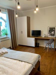 a bedroom with a bed and a desk with a television at Водограй, курортна вілла in Morshin