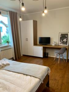1 dormitorio con 1 cama y escritorio con TV en Водограй, курортна вілла, en Morshyn