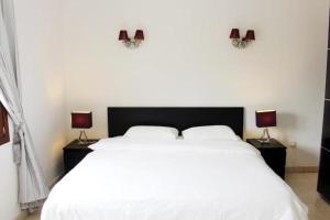 a bedroom with a large white bed with two lamps at NOOR PLAZA BEACH FURNISHED FLATS in Salalah