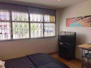 um quarto com uma cama, uma televisão e janelas em COSY STUDIO APARTMENT GREAT LOCATION (203) em Bogotá