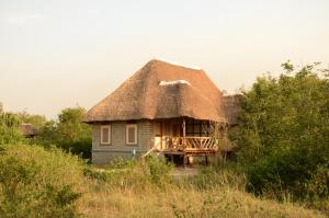 małą chatę z dachem krytym strzechą na polu w obiekcie Irungu Forest Safari Lodge w mieście Katunguru