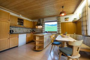 una cocina con armarios de madera, mesa y sillas en Ferienhof Alfred Albrecht, en Oberstdorf