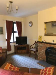a living room with a television and a fireplace at Gilmore House in Ardglass