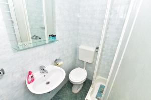 a white bathroom with a toilet and a sink at Apartmani Tome in Zadar