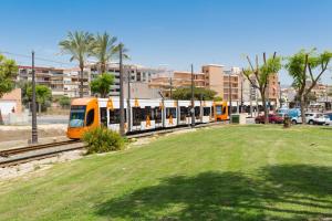 an orange and white train on tracks in a city at Hostal12 in El Campello