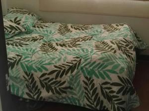 uma cama com um edredão verde e branco em Habitaciones Altos de Cooservicios em Tunja