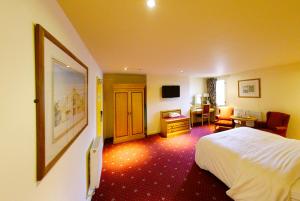 a hotel room with a bed and a desk and a chair at Three Queens Hotel in Burton upon Trent