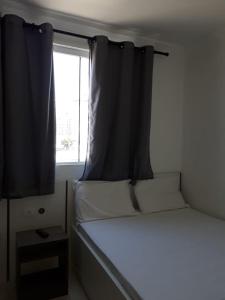 a small bedroom with a bed and a window at Hotel Lisboa in Curitiba