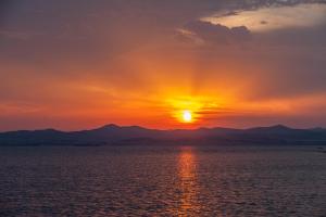 モウドロスにあるTo Kymaの山を背景に海に沈む夕日