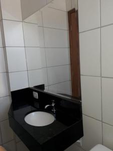 a bathroom with a sink and a black counter at Hotel Lisboa in Curitiba