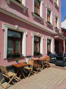 różowy budynek ze stołami i krzesłami przed nim w obiekcie Penzion U Papoušků w mieście Jindrichuv Hradec