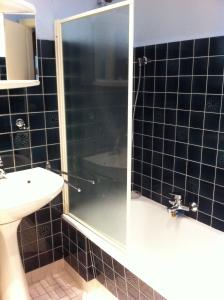 een zwart betegelde badkamer met een douche en een wastafel bij GITE CHEZ JEAN PAUL in Fréland