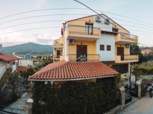 a yellow and white house with a red tile roof at Hotel Karagiannis in Limenaria