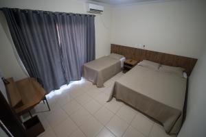 Habitación pequeña con 2 camas y ventana en Hotel Campo Verde, en Dourados