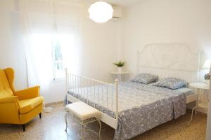 sypialnia z białym łóżkiem i żółtym krzesłem w obiekcie Punta Prima beach apt Orihuela Costa w mieście Punta Prima