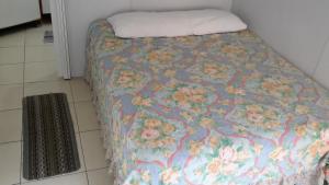 a bed with a blanket with flowers on it at Apartamento Blue Sky in São Vicente