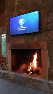 a fireplace with a tv above it with a fire at Hostería Bärenhaus in San Martín de los Andes