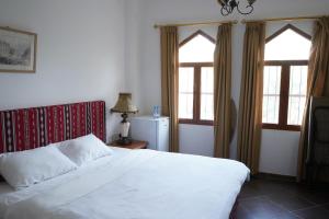 um quarto com uma cama branca e 2 janelas em Date Palm Inn em Nizwa