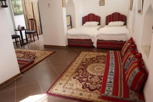 two beds in a room with two rugs at Date Palm Inn in Nizwa