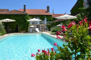 a swimming pool with pink flowers and umbrellas at La Baguenaude in Marciac