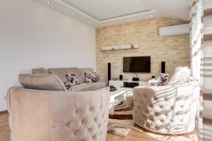 a living room with two chairs and a tv at DiVino Apartment in Tivat