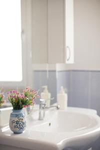 ein Waschbecken mit einer Vase mit Blumen im Bad in der Unterkunft Casa Vacanza AZZURRA in Cinisi