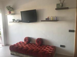a red couch in a living room with a flat screen tv at Cabobeach Appartement in Cabo Negro