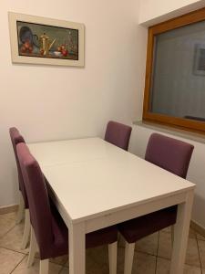 a white table with purple chairs and a window at Villa Saline Apartments Portorož in Portorož