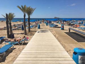a wooden pathway on a beach with people laying on chairs at Apartamento AGUA MARINA Levante Beach in Benidorm