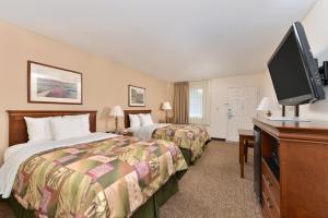 um quarto de hotel com duas camas e uma televisão de ecrã plano em The Heritage Inn, Inc em Huntingdon