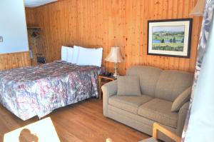 ein Schlafzimmer mit einem Bett, einem Sofa und einem Stuhl in der Unterkunft Bay Vista in Cavendish