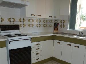 a white kitchen with a stove and a sink at The Breakers 13 in Forster
