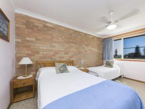 a bedroom with two beds and a brick wall at Fairholme 12 in Tuncurry