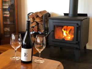 a bottle of wine and two glasses on a table with a stove at The Residence @ Elbourne Wines in Lovedale