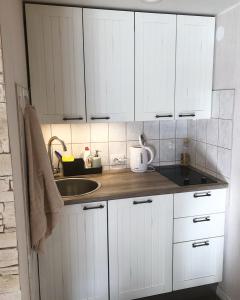 a kitchen with white cabinets and a sink at Markuse puhkemaja in Palamuste