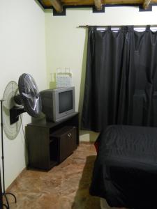 Malargue Style a 100 MTS del Centro في مالارغي: غرفة نوم بسرير وتلفزيون ومروحة