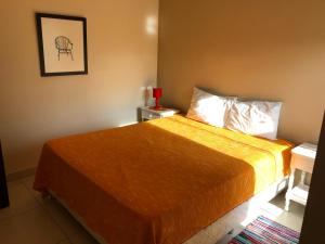 a bedroom with a bed with a orange bedspread at Madre Natura in Asuncion