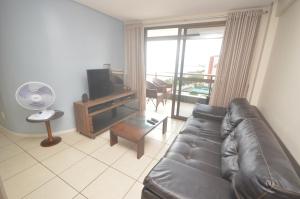 a living room with a leather couch and a television at Leme Penthouse Apartment in Fortaleza