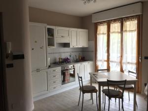 アルゲーロにあるCozy Apartment in Algheroの白いキャビネット、テーブルと椅子付きのキッチンが備わります。