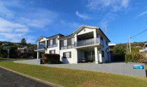 a white house with a balcony on a street at Dolphin Court 1, 1 Gowing Street in Crescent Head