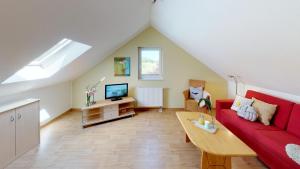 a living room with a red couch and a tv at Feriendorf Südstrand Haus 09 in Pelzerhaken