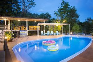 una gran piscina con patio y una casa en Tharapana Khaoyai Resort en Mu Si