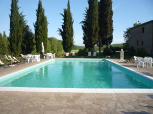 une piscine avec des tables, des chaises et des arbres dans l'établissement Agriturismo Natura E Salute, à San Gimignano