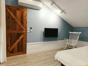 台東市にあるEasy Life B&Bのベッドと壁にテレビが掛かった寝室