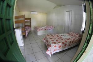 a room with three beds in a room with a door at Pousada Cataventos in Sirinhaém